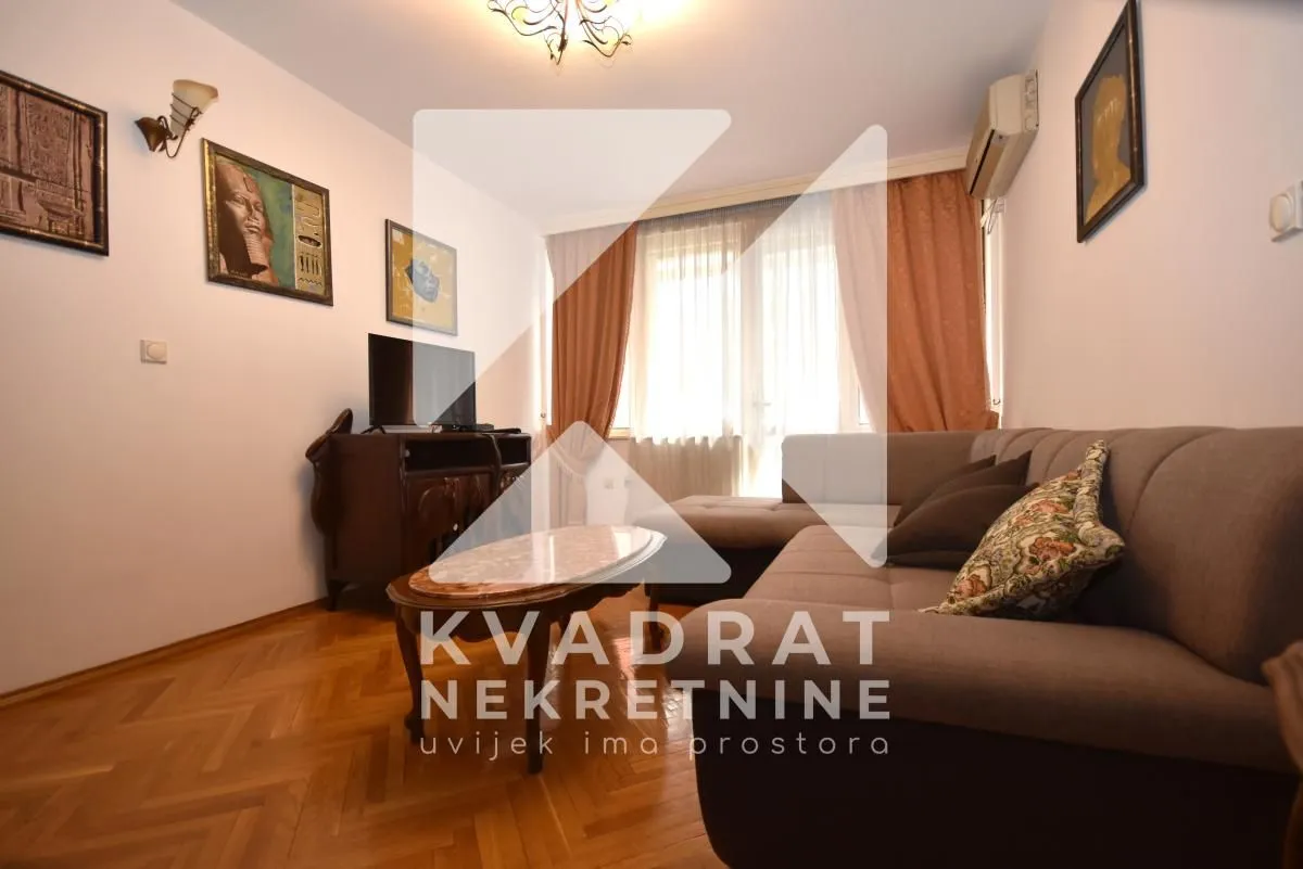 Living room with a sofa set, television, and parquet flooring.