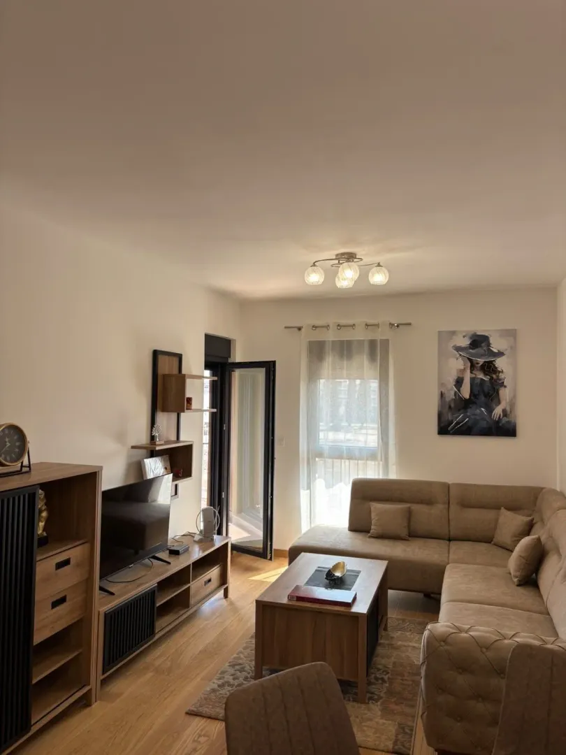 Living room with a sectional sofa, TV unit, and access to the terrace.