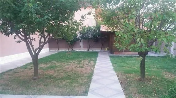 A landscaped yard with a paved pathway and trees in front of the house.