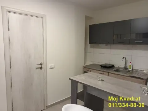 Small kitchen with dark wall cabinets and a dining table. - image 2