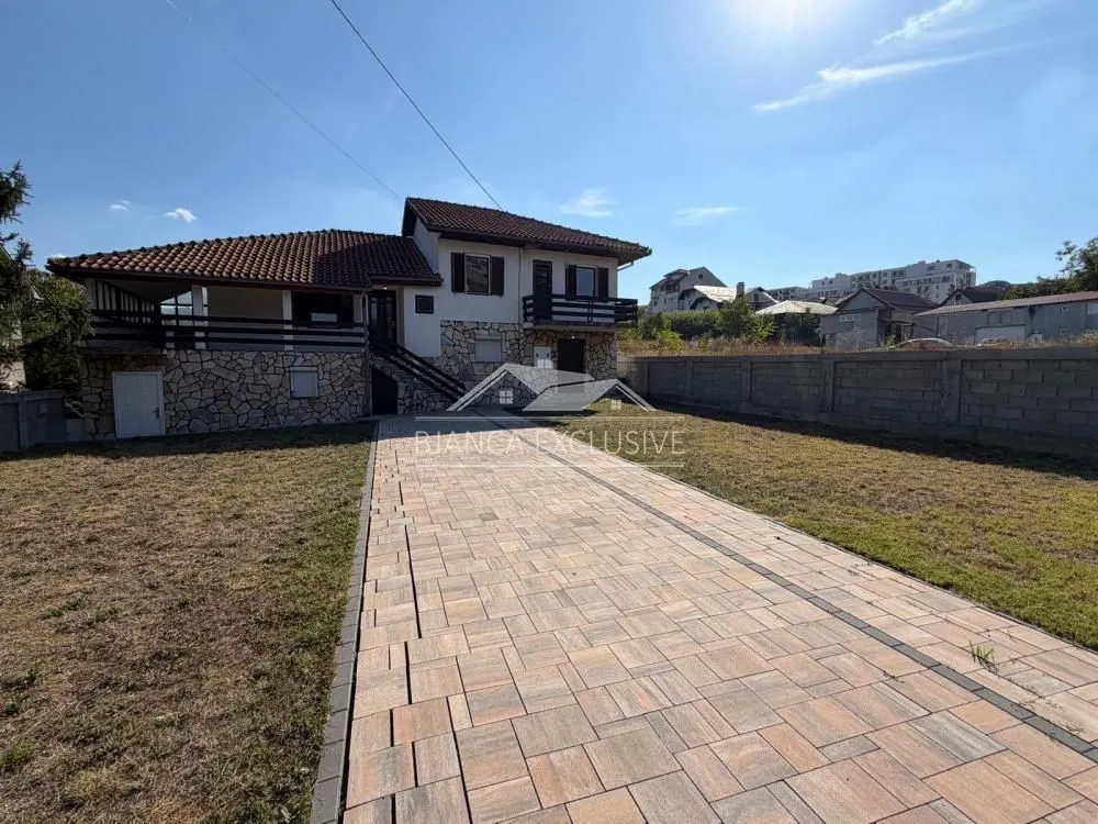 Pogled na dvorište i spoljašnjost kuće sa popločanim prilazom.