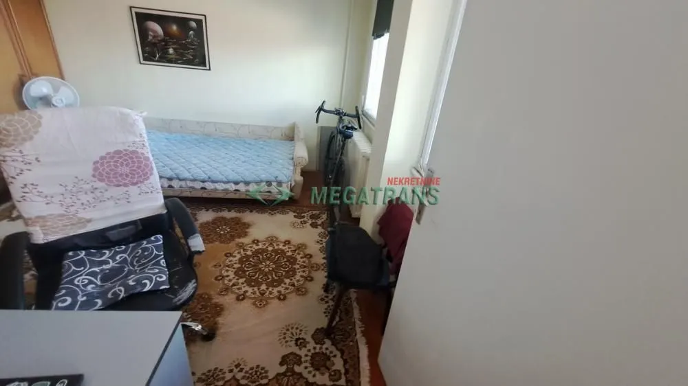 Manja spavaća soba sa krevetom, radnim stolom i tepihom.
