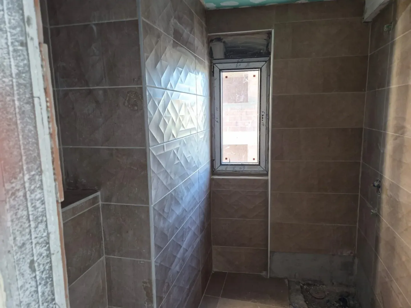 Bathroom during final ceramic installation work with a window.