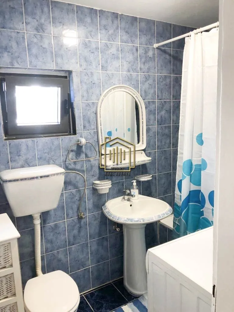 Kupatilo obloženo pločicama sa umivaonikom, ogledalom i toaletom.