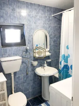 Kupatilo obloženo pločicama sa umivaonikom, ogledalom i toaletom. - image 6