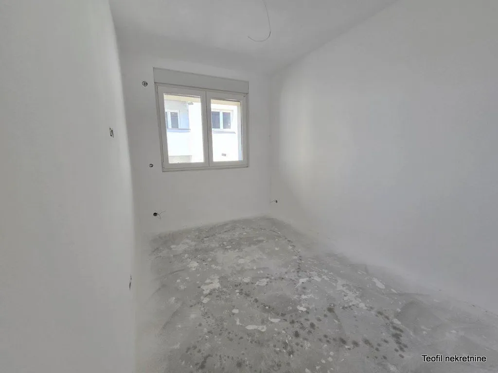 Prazna neuređena prostorija sa belim zidovima i prozorom.
