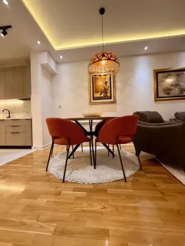 Living room with a dining area, wooden flooring, and modern lighting. - image 3