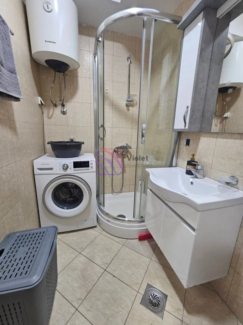 Bathroom equipped with a shower cabin, washbasin, water heater, and washing machine.