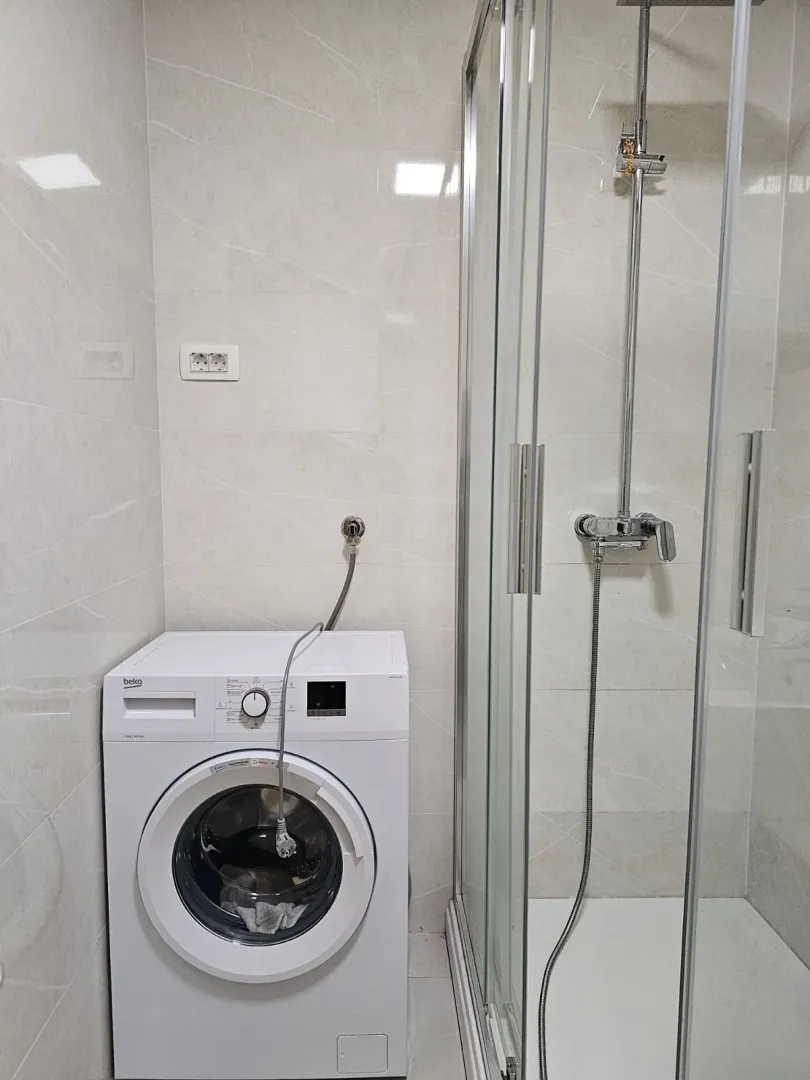 Bathroom with a washing machine and a shower cabin.