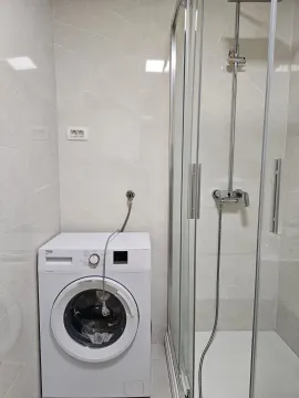 Bathroom with a washing machine and a shower cabin. - image 7