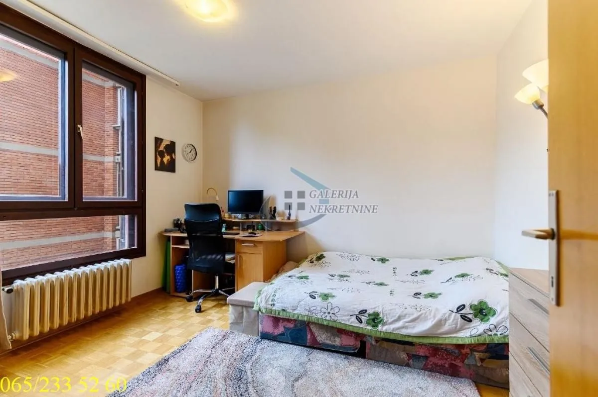 Small bedroom with a bed, desk, and window.