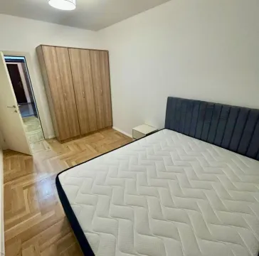 Spavaća soba sa bračnim krevetom, drvenim ormarom i parketom. - image 6