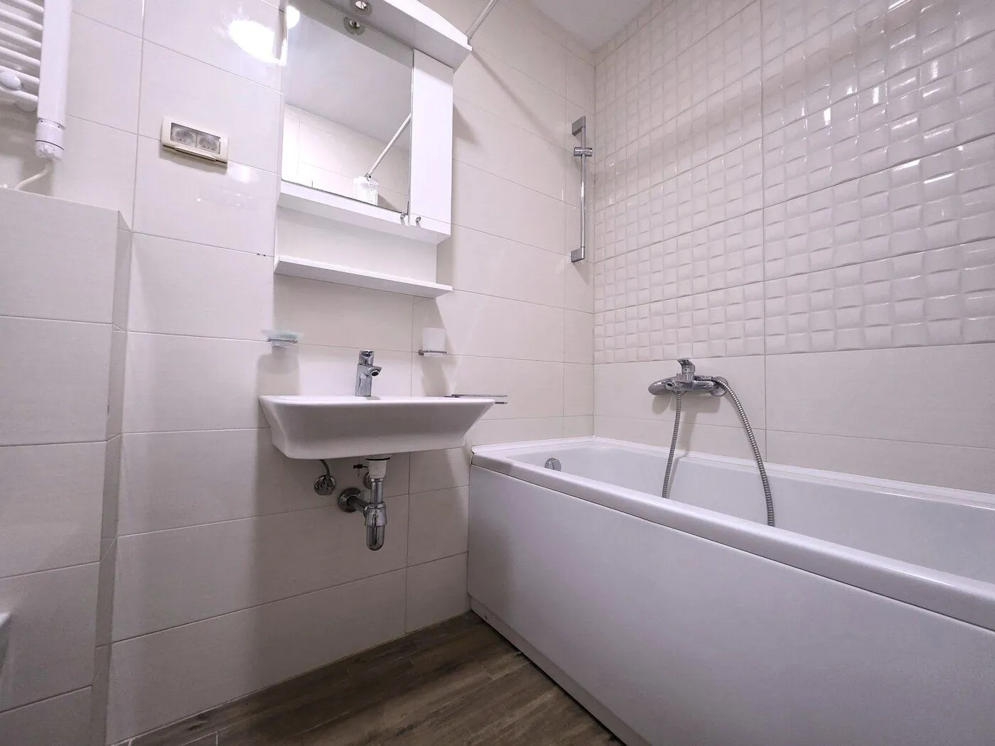Bathroom equipped with a sink, a mirror, and a bathtub with a shower mixer.