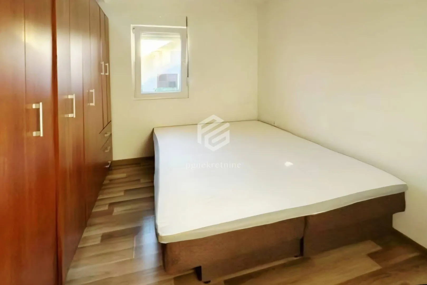 Furnished bedroom with a double bed and a large wooden wardrobe.