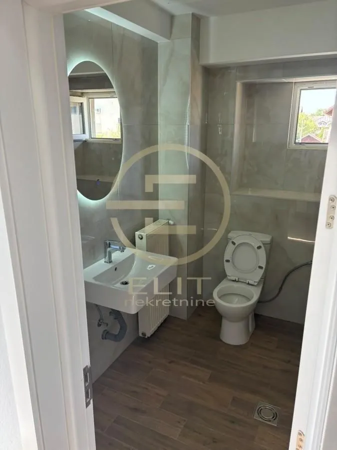 Small bathroom with a sink, toilet, and window.