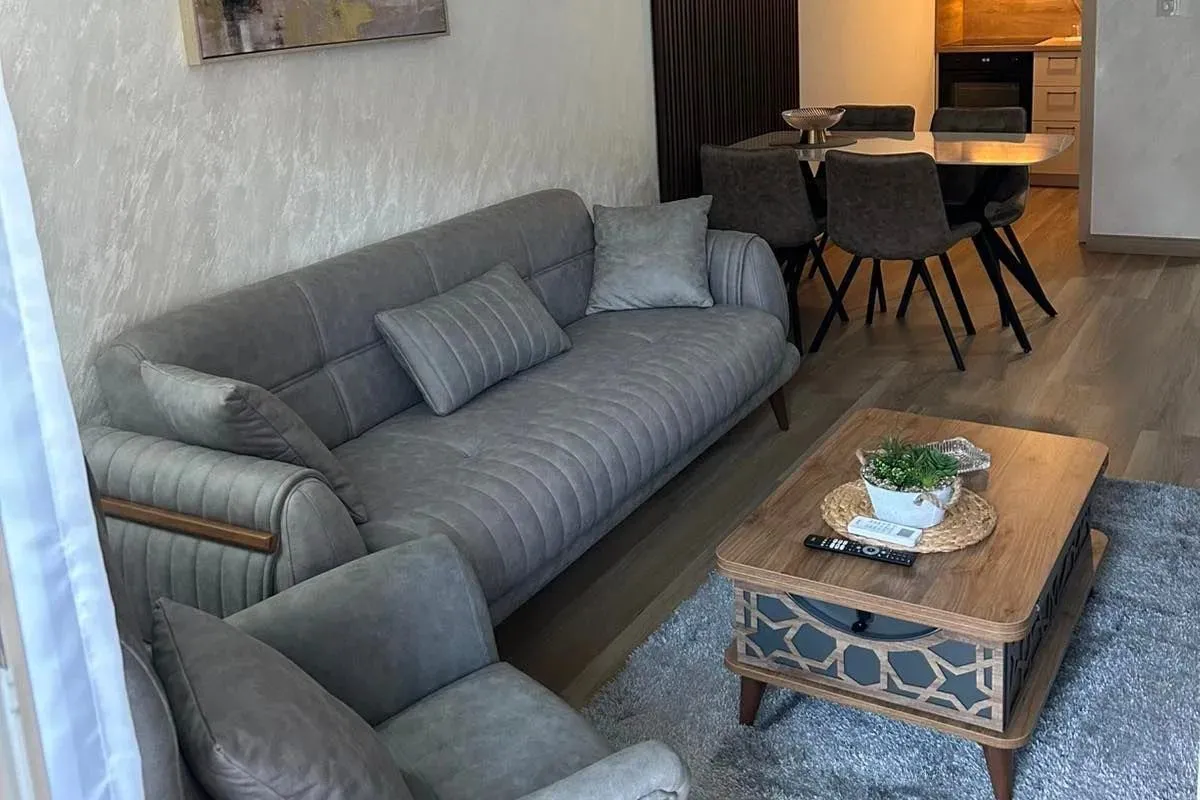 Dnevni boravak sa garniturom i trpezarijom u pozadini.
