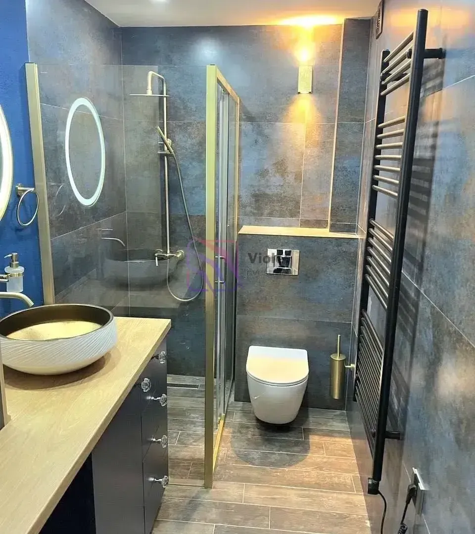 Moderno opremljeno kupatilo sa tuš kabinom, umivaonikom i WC šoljom.