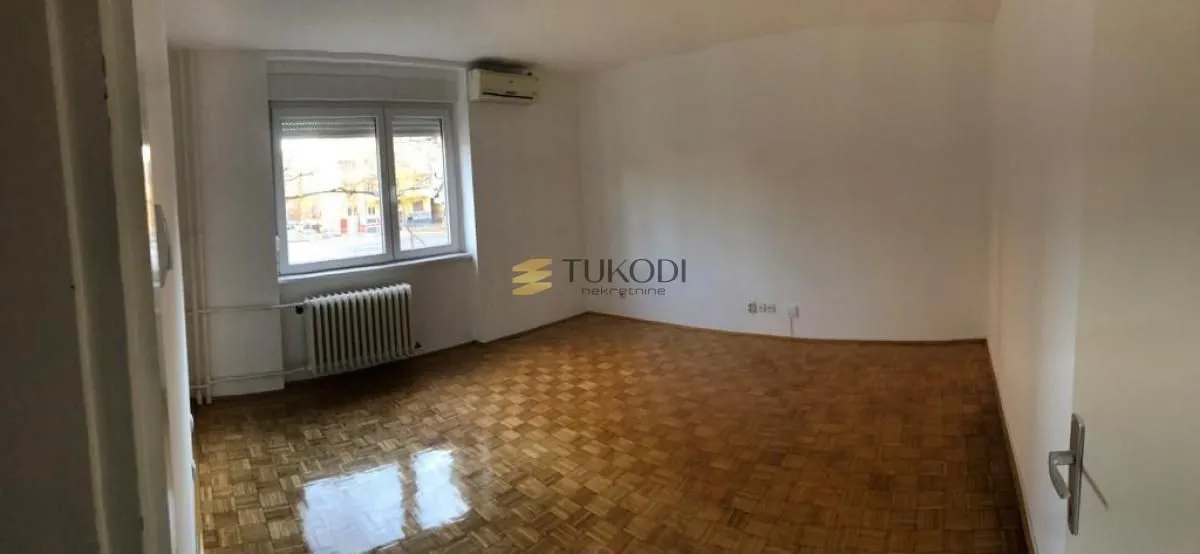 Prazna soba sa parketom i prozorom.