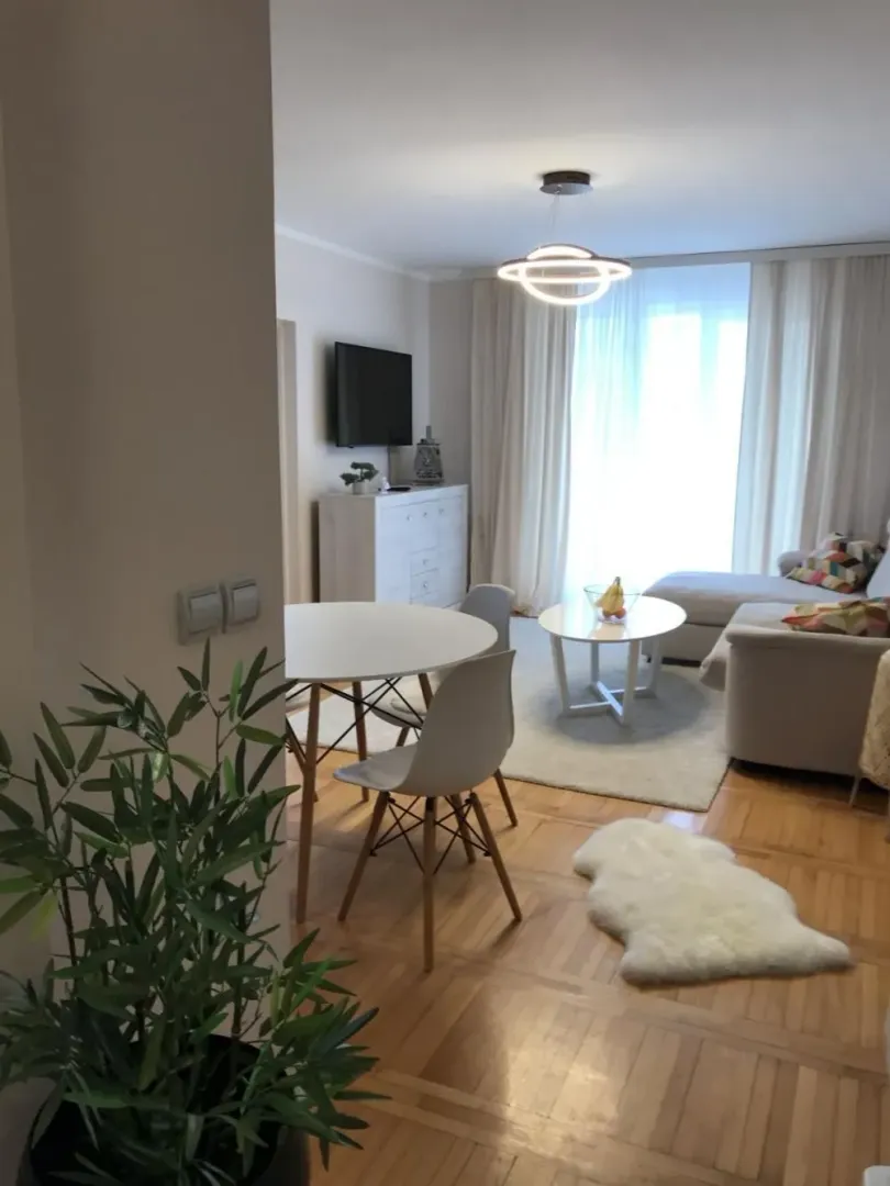 Living room with sofa, dining table, and parquet flooring.