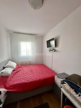 Manja spavaća soba sa bračnim krevetom i zidnim televizorom. - image 8