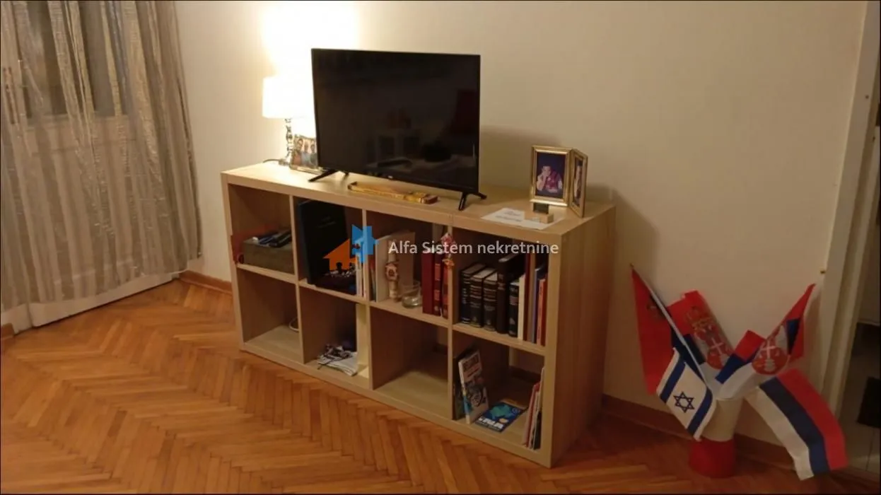Dnevna soba sa TV komodom i parketom na podu.