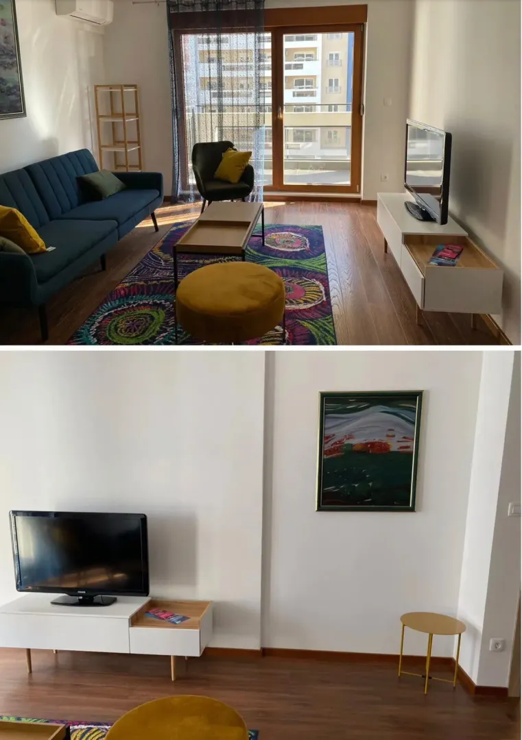 Dnevna soba sa garniturom, TV-om i izlazom na balkon.