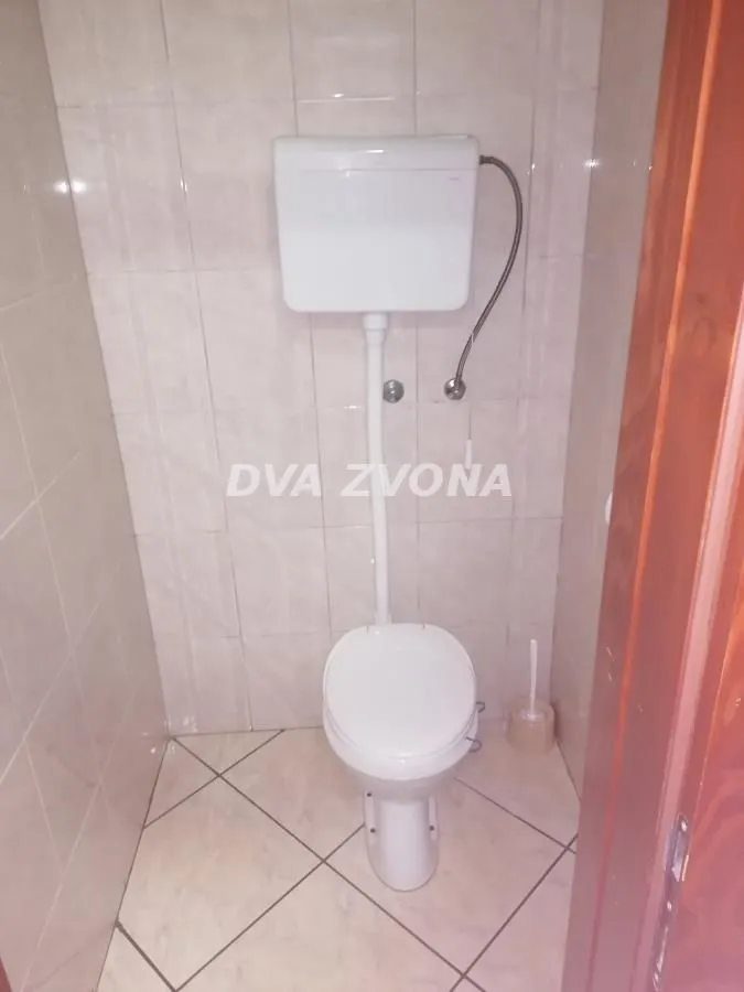 Small bathroom tiled with ceramic tiles containing a toilet.
