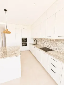 Modern white kitchen with marble countertop and built-in appliances. - image 8