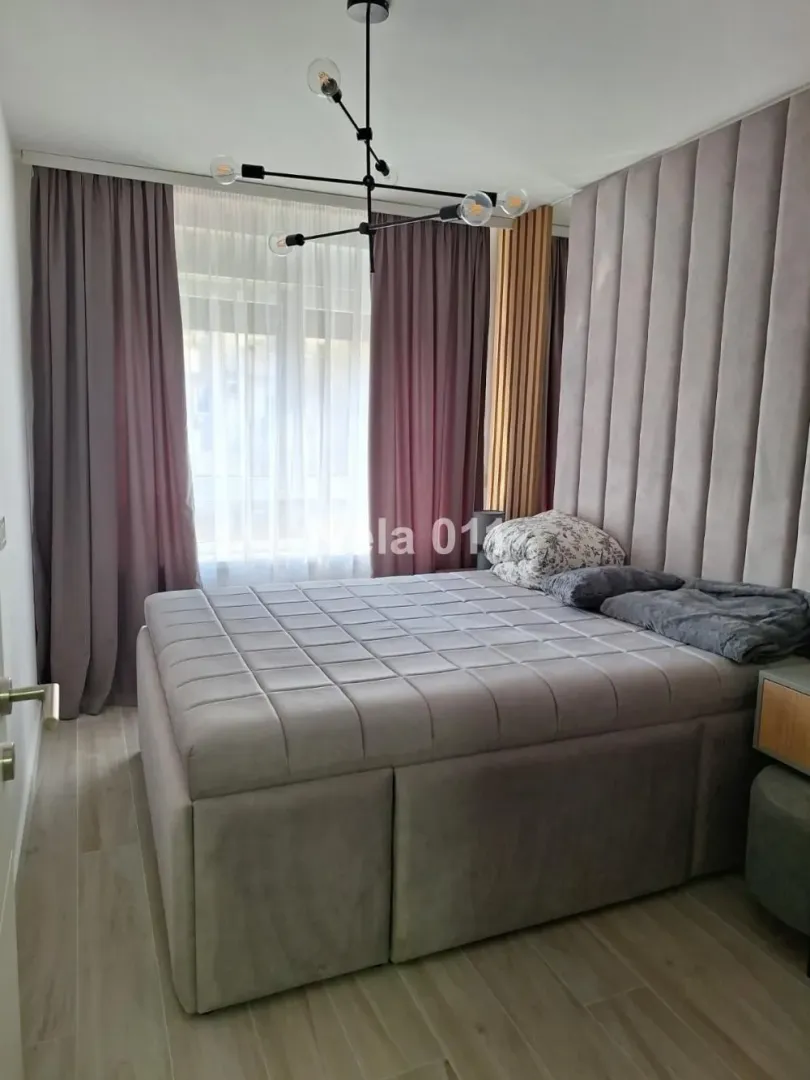 Moderna spavaća soba sa bračnim krevetom i tapaciranim uzglavljem.