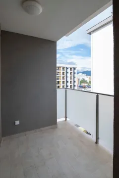 An empty balcony with a glass railing and a view of surrounding buildings. - image 11