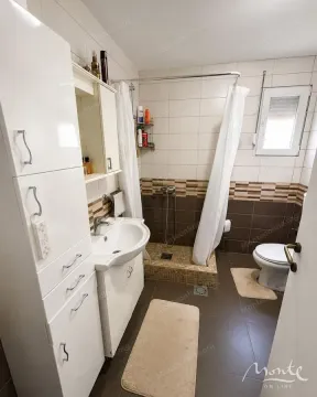 Kupatilo opremljeno umivaonikom, tuš kabinom, WC šoljom i bijelim ormarićem. - image 12
