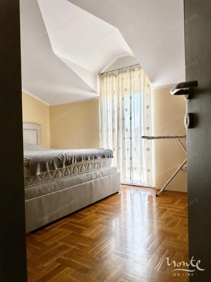 View from the hallway into the bedroom with a bed and balcony access.