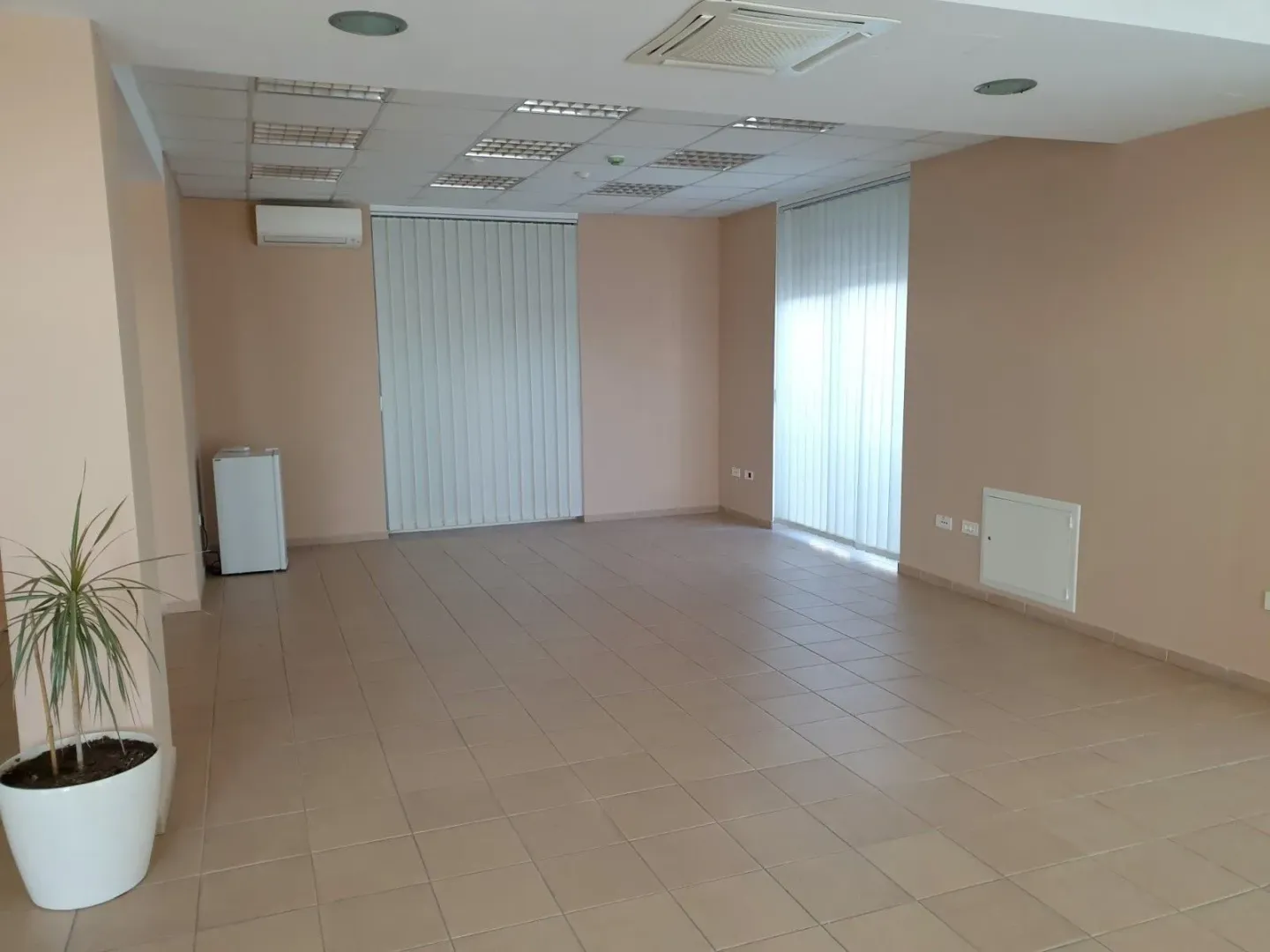A spacious empty room with tiled flooring, suitable for an office or commercial space.