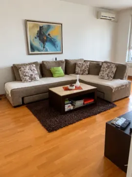 Living room with a corner sofa, coffee table, and a painting on the wall. - image 14