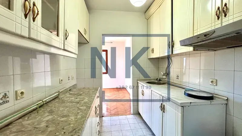 Manja kuhinja sa bijelim elementima i radnom površinom.