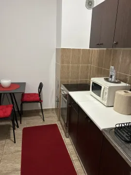 Jednostavna kuhinja sa trpezarijskim stolom i tamnim elementima. - image 6