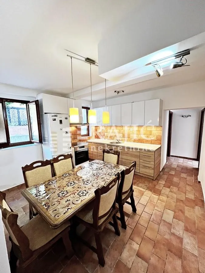 Dining area with a wooden table and chairs and a kitchen in the background.