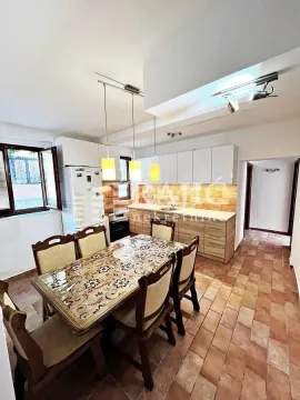 Dining area with a wooden table and chairs and a kitchen in the background. - image 7