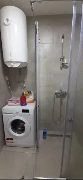 A bathroom featuring a shower cabin, washing machine, and water heater. - image 3