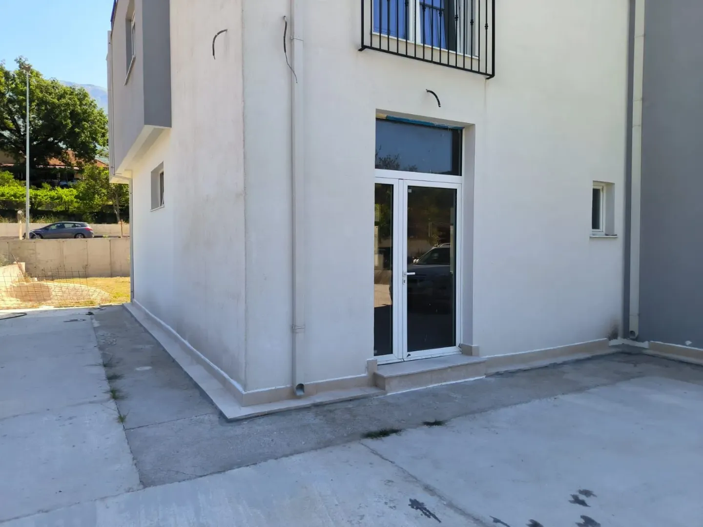 Exterior view of the building with an entrance door and concrete yard.