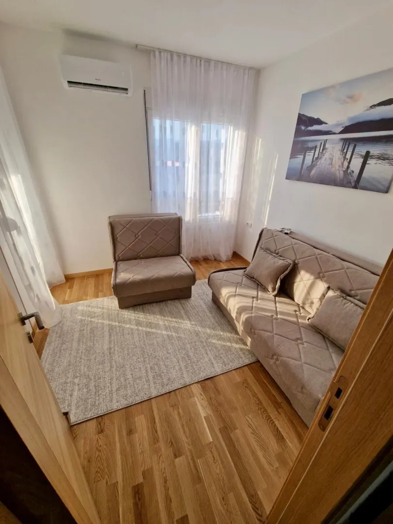 Manji svijetli dnevni boravak sa bež garniturom i laminatom.