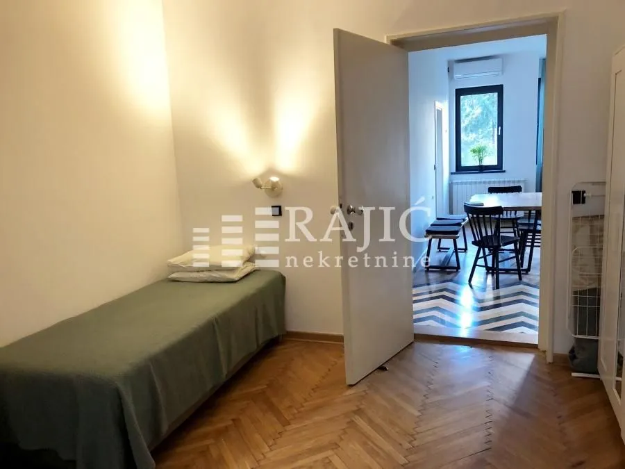 Small bedroom with a single bed and an open passage to the dining area.