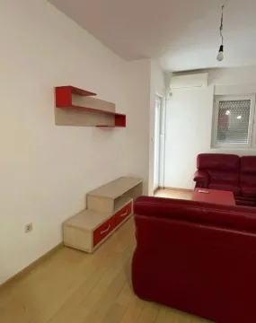 Dnevna soba sa crvenom garniturom i TV komodom. - image 2