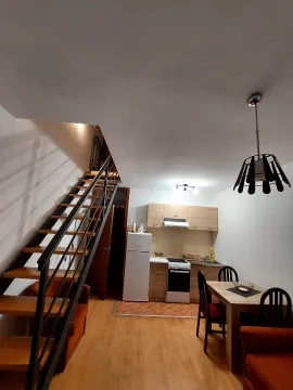 Living room with kitchen, dining area, and stairs leading to the upper floor. - image 3
