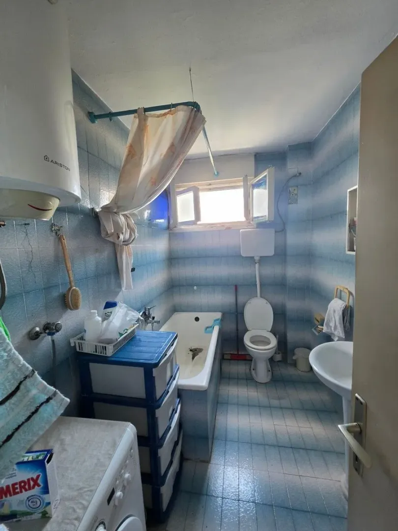 Starije opremljeno kupatilo sa kadom, wc šoljom i umivaonikom.