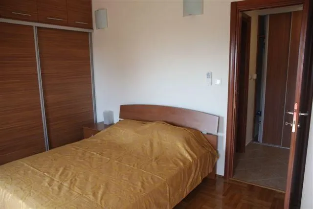 Svijetla spavaća soba sa velikim bračnim krevetom i ugradnim plakarom.