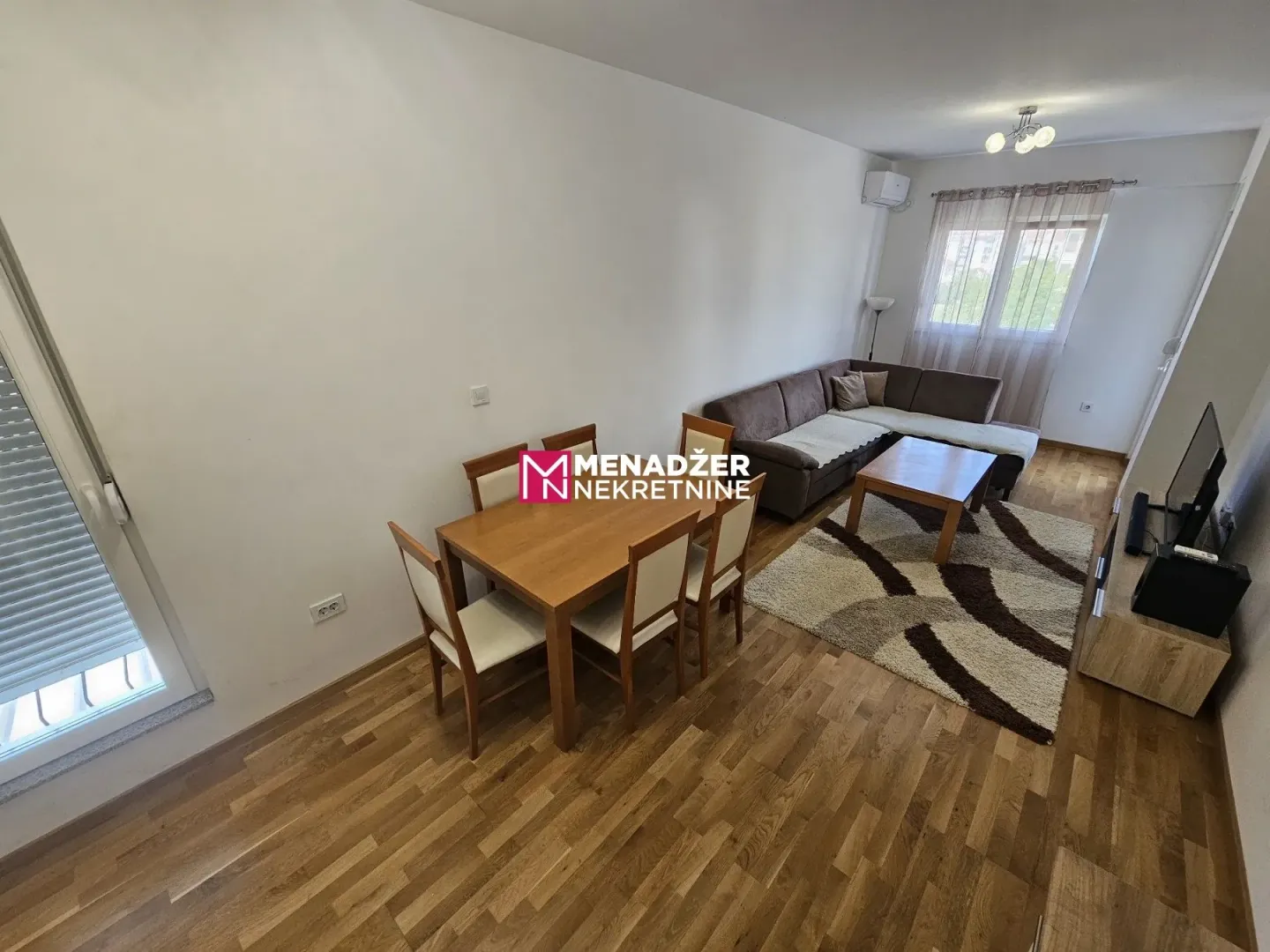 Living room with dining area, sofa set, and wooden flooring.