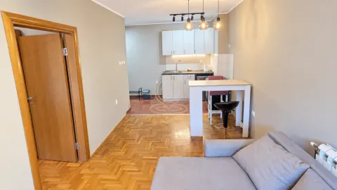 Living room with a sofa and a view of the open kitchen with a dining counter. - image 4