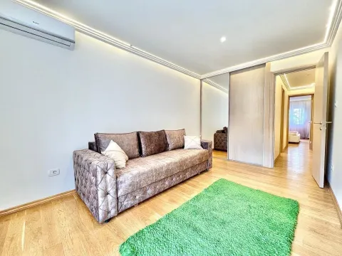Bright room with a sofa and a green rug. - image 2
