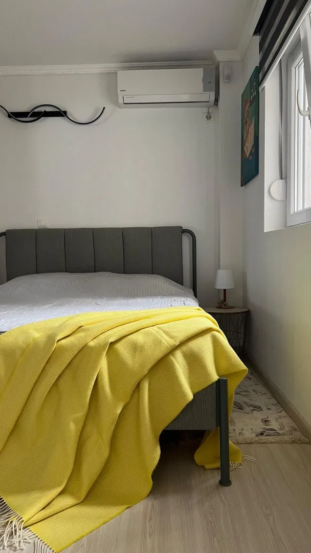 Namještena spavaća soba sa bračnim krevetom i žutim prekrivačem.